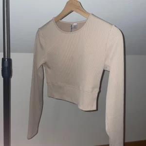Beige ribbad tröja  - Snygg beige ribbad tröja från med långärmad design. Enkel och stilren med en croppad passform.