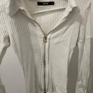Vit ribbad tröja med dragkedja från Bik Bok - Säljer en stilren vit ribbad tröja från Bik Bok i storlek XS. Tröjan har en dragkedja framtill och en klassisk krage. Perfekt för en avslappnad men ändå snygg look. Använd 3 gånger Max, köpt för 2 år sedan !!!