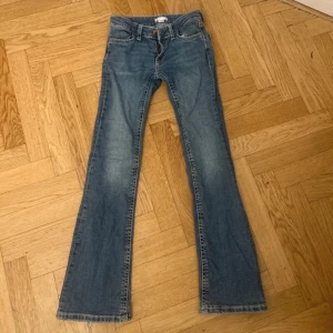 Blå bootcut jeans - Snygga blå bootcut jeans med låg midja. Perfekta för en avslappnad stil. Klassisk design med dragkedja och knapp framtill.