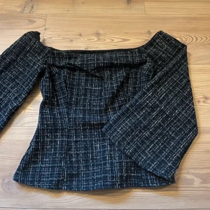 Svart offshoulder topp från Zara - Snygg svart offshoulder topp från Zara med ett rutigt mönster i vitt. Toppen har vida ärmar och en elegant passform som passar perfekt för en stilren look.