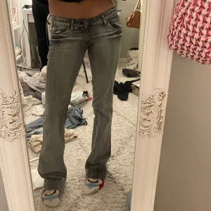 Lågmidjade jeans - Säljer ett par grå bootcut jeans med låg midja. Lite slitna vilket jag lagt in bilder på och de saknar storlek men skulle säga att de är xs💓Innerbenslängden är runt 84 cm😇
