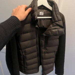 Mörkgrön dunjacka från C.P. Company - Mörkgrön/olive dunjacka/cardigan från C.P. Company. Jackans framsida är av dun och baktill samt ärmar i tyg. Sparsamt använd därmed mycket bra skick. Jackan säljer jag något billigare då jag inte hittat huvan till den.