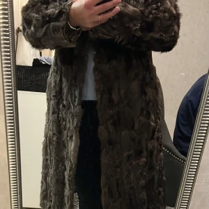 Brun pälsjacka från Fuchs - Säljer en elegant brun pälsjacka från Fuchs. Jackan har en lång design med långa ärmar och en mjuk, lyxig känsla. Perfekt för att hålla sig varm och stilren under kyliga dagar.