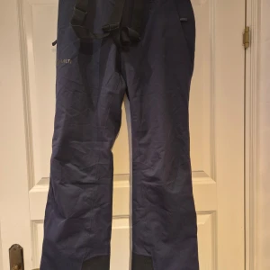 Slalombyxor från Halti - Säljer ett par blå slalombyxor från Halti med Drymax® Ultimate stretchmaterial och Microtherm isolering. Byxorna har vattentäta sömmar och dragkedja vid benslut med snölås. Reglerbar midja med kardborre.  Mycket sparsamt använda. 