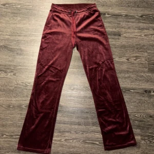 Vinröda byxor från Gina Tricot - Snygga vinröda byxor från Gina Tricot i mjukt sammetstyg. De har en bekväm loose passform och är högmidjade med knytband i midjan för justerbar passform. Perfekta för en avslappnad stil.