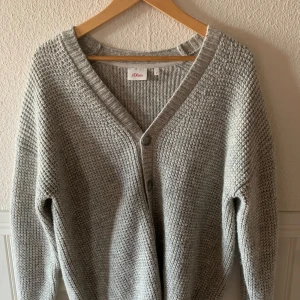 Grå stickad kofta från s.Oliver - Mysig grå stickad kofta från s.Oliver med v-ringning och fräscha knappar. Perfekt för kyligare dagar. Mitt pris är 300kr! (!obs!Köparen står för frakt!)