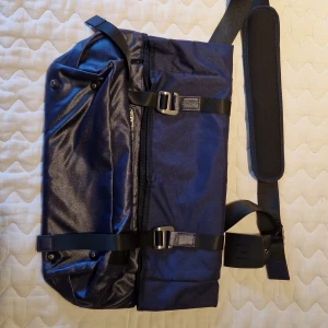 Svart axelväska från Don Donna - Snygg svart axelväska från Don Donna med justerbar axelrem och flera praktiska fack. Väskan har en stilren design med spännen och dragkedja för säker förvaring. Perfekt för vardagsbruk eller resor.