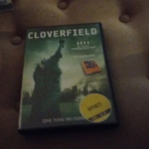 Cloverfield DVD - Säljer en DVD av filmen Cloverfield. Omslaget visar Frihetsgudinnan i en dramatisk scen med en mörk och mystisk bakgrund. Perfekt för filmkvällar med spänning och action.