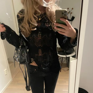 Svart spetsblus - Snygg svart spetsblus med långärmad design och ett genombrutet mönster. Perfekt för en stilren look med en touch av elegans. Blusen har en figurnära passform och är idealisk för att lyfta vilken outfit som helst.  Ifrån Zara i mycket bra skick. I storlek S