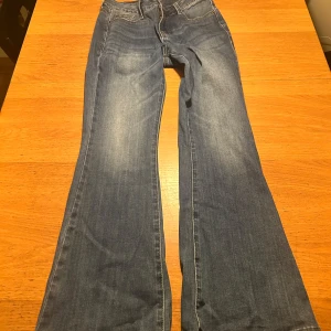 Blå bootcut jeans från Madlady - Säljer ett par snygga blå bootcut jeans från Madlady. De har en klassisk femficksdesign och är perfekta för en avslappnad stil. Passar bra till både sneakers och klackar. Storlek 36/short, passar folk som är mellan 160-165 skulle ja säga. Normala i storleken!