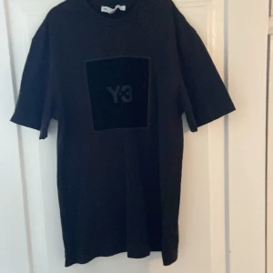 Svart t-shirt från Y-3 - Säljer en svart t-shirt från Y-3 med en stor logga på framsidan. T-shirten har korta ärmar och en normal passform. Perfekt för en stilren och modern look.
