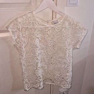Vit spetsblus från Gina Tricot - Säljer en vacker vit spetsblus från Gina Tricot. Blusen har korta ärmar och ett detaljerat blommönster. Perfekt för en somrig look! Stl 34