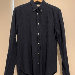 Mörkblå skjorta från Dobber - Snygg mörkblå skjorta från Dobber i storlek S. Skjortan har långa ärmar och knappar framtill samt en bröstficka. Perfekt för en stilren look.