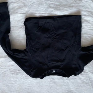 Svart långärmad gym topp från H&M - Snygg svart långärmad gym topp från H&M. Perfekt för en stilren look. Tillverkad i ett mjukt material som ger en bekväm passform.