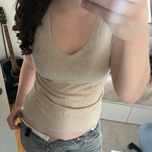 Beige V-ringad topp från Ralph Lauren - Säljer en beige V-ringad topp från Ralph Lauren. Toppen har en figurnära passform och är tillverkad i mjukt bomullsmaterial. Perfekt för en avslappnad men ändå elegant look.