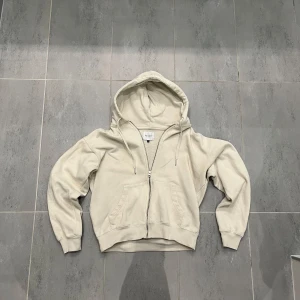 Beige hoodie från Valient - Säljer en stilren beige hoodie från Valient i storlek M. Den har en dragkedja framtill och en praktisk huva. Perfekt för en avslappnad look.