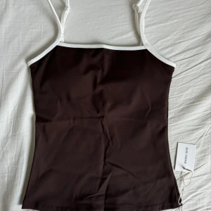 exercere active tank top - Jag råkade köpa två likadana träningslinnen, därav säljer jag denna. Det är ett helt nytt brunt träningslinne från märket Exercere. Linnet har justerbara band och en inbyggd sport-bh med uttagbara inlägg. Super snygg och bekväm att träna i eller att ha till vardags! Den är helt slutsåld på hemsidan. Nypris 765 kr