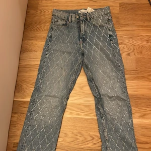 Blå jeans med rutigt mönster - Snygga blå jeans med ett unikt rutigt mönster. De har en klassisk femficksdesign och raka ben. Perfekta för en stilren look.