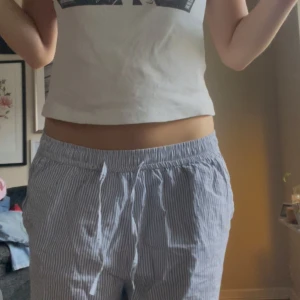 Randiga mjukisbyxor - Säljer ett par superbekväma randiga mjukisbyxor i blått och vitt. De har en loose passform och är perfekta för en avslappnad dag hemma. Byxorna har en elastisk midja med snörning för extra komfort.