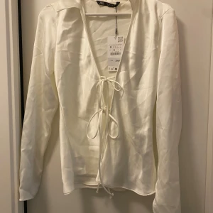 Knyt blus - Fin lite figursydd knyt blus/skjorta i satin material. Ärmarna har en slit i sig som syns på bilderna. Endast testad med prislappen kvar.    Stl. M men passar även en S. 