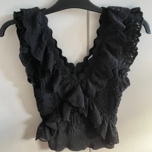 Svart spetslinne från Zara - Säljer ett snyggt svart spetslinne från Zara. Det har en v-ringad design med volanger som ger en romantisk touch. Perfekt för en utekväll eller fest! 🖤