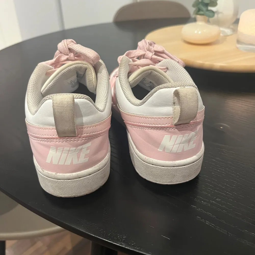 Säljer ett par snygga Nike sneakers i rosa och vit. De har en klassisk design med snörning och en bekväm passform. Perfekta för vardagsbruk eller en avslappnad dag ute. Skorna är i bra skick och redo för en ny ägare!. Skor.