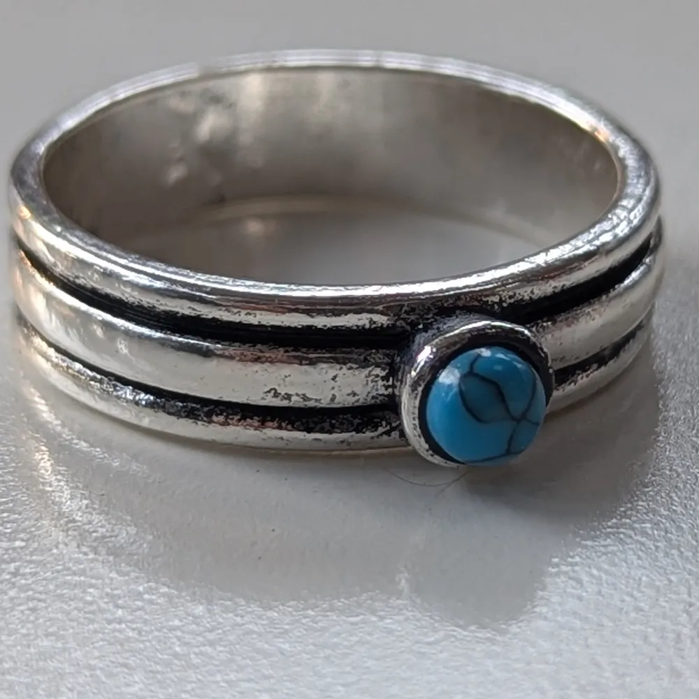 Säljer en snygg silverring med en liten turkos sten i mitten. Ringen har en enkel men stilren design med dubbla linjer som ramar in stenen.koppar material storlek 11 ( 20.7 diameteren). Asusteet.