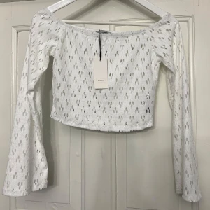 Vit långärmad topp med hålmönster - Säljer min vita topp från Only. Toppen är croppad och har en offshoulder-design. Storlek S. Aldrig använd, därav prislappen kvar.