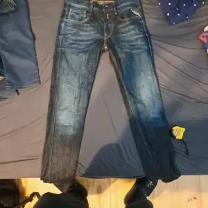 Säljer ett par snygga Replay Anbass jeans i mörkblå denim. De har ett coolt FC Barcelona-märke på insidan av midjan, vilket gör dem unika. Jeansen har en klassisk femficksdesign och en bekväm passform. Perfekta för både vardag och fest!