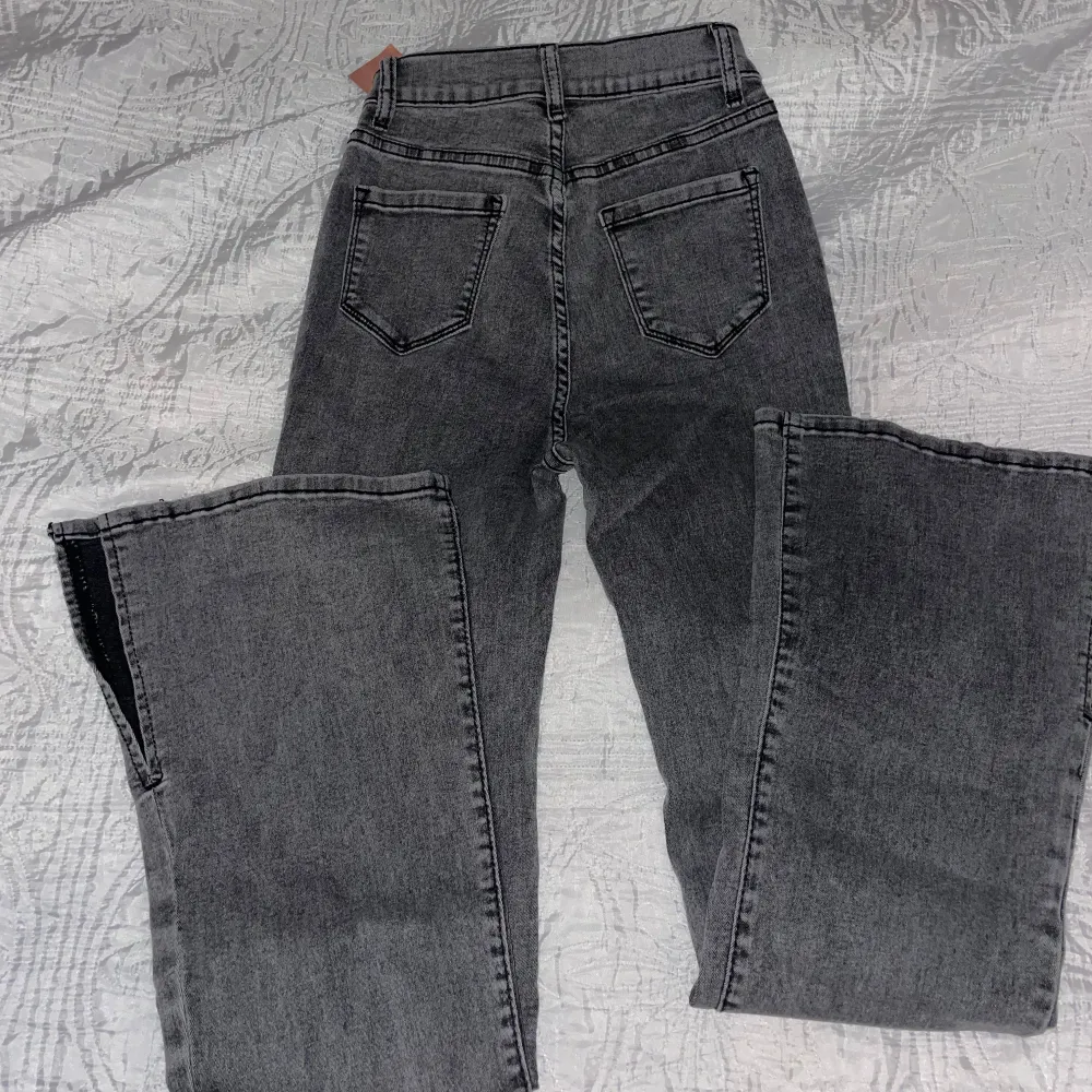 Gråa jeans med utsvängda ben och fållen slits.   Storlek W26 L32:  Längd - 113 cm Midjastorlek - 61.5 cm Höft storlek - 83 cm Lår - 51.2 cm  Aldrig använda, prislapp kvar.  Nypris: 289kr. Jeans & Byxor.