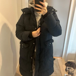 Lång vinterjacka  - En lång vinterjacka från lager 157 med rymliga fickor. Superskön och mysig! Är väldigt mörk marinblå och i fint skick. Storlek M men beror på hur man vill passformen ska vara, jag har i vanliga fall S
