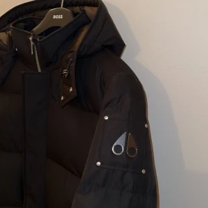 Svart dunjacka från Moose Knuckles - Säljer en svart vinterjacka från Moose Knuckles med avtagbar huva och dragkedja. jackan har använts ungefär 2-3 gånger. Säljer den pga att den inte används längre jackan är i storlek XXL me den passar perfekt för den som har XL. Priser går även att diskuteras!! 