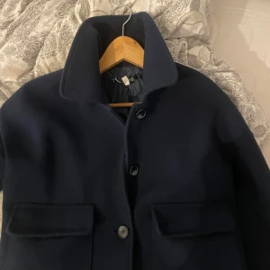 Mörkblå kort kappa design by si  - Elegant mörkblå kappa med knappar framtill och stora fickor. Använd fåtal gånger så väldigt bra skick, hör av er för mer info o bilder 💕💕🎀🎀