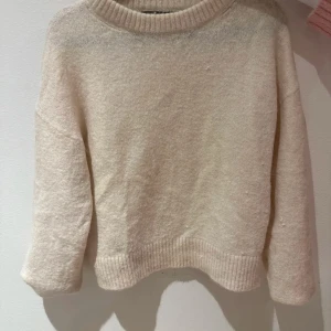 Beige tröja från Bik Bok - Mysig beige tröja från Bik Bok i alpackablandning. Tröjan har en rund halsringning och långa ärmar, perfekt för kyligare dagar. Materialet består av polyester, alpacka och polyamid vilket ger en mjuk och bekväm känsla.