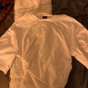 Vit t-shirt  - Säljer en klassisk vit t-shirt från Asos. Perfekt basplagg med normal passform och korta ärmar. Tillverkad i mjuk bomull för en skön känsla hela dagen.