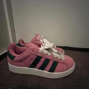 Rosa Adidas Campus sneakers - Snygga rosa Adidas Campus sneakers i mocka med gröna ränder och vita snören. Aldrig kommit till användning och säljer därför vidare! Skriv för mer info!🩷nypris 1500kr