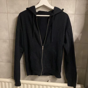 Svart hoodie från Even&Odd - Säljer en svart hoodie från Even&Odd med dragkedja framtill. Tröjan har långa ärmar och en praktisk huva. Perfekt för en avslappnad stil.