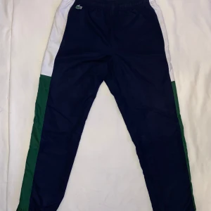 Lacoste Track Pants - Säljer ett par snygga mjukis från Lacoste. Storlek S, 3 FR (kan passa M) Färg, blå och grön men vita detaljer. Cond, 9/10