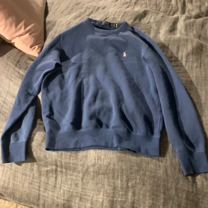 Blå tröja från Polo Ralph Lauren - Säljer en stilren blå tröja från Polo Ralph Lauren med en liten broderad logga på bröstet. Tröjan är i jättefint skick då den är använd Max 5 gånger. Tveka inte att höra av er vid intresse.