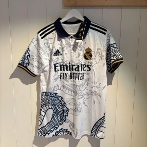 Real madrid dragon tröja - Säljer den riktigt coola real Madrid tröjan från 2022. Den finns i storlek M x2 och en S. Denna annons är storlek M. Hör av dig vid minsta fundering!