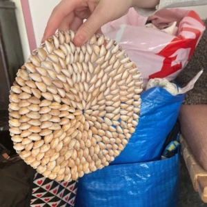 Rund dekoration med snäckor - En rund dekoration täckt med små, vita och beige snäckor arrangerade i ett tätt mönster. Perfekt som en unik inredningsdetalj för att ge en naturlig och strandinspirerad känsla till ditt hem.