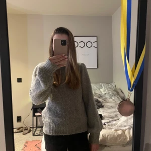 Grå stickad tröja från Gina Tricot - Säljer en mysig grå stickad tröja från Gina Tricot. Tröjan har en klassisk design med långa ärmar och ribbade muddar vid ärmslut och nederkant. Perfekt för kyligare dagar. Obs! Den är liten i storleken. 