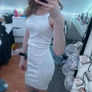 Vit ärmlös klänning  - Säljer en stilren vit ärmlös klänning med en tight passform. Perfekt för sommarens varma dagar. Klänningen har en enkel design som gör den lätt att matcha med olika accessoarer.