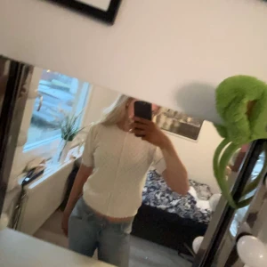 Vit kofta från Bisou's Project - Säljer en söt vit kofta från Bisou's Project med ett diskret rutmönster. Koftan har korta ärmar och knappar framtill. Perfekt för en stilren look. Aldrig använd. Liten i storleken.