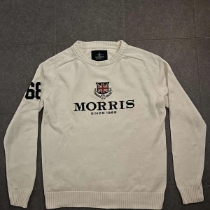 Vit tröja från Morris - Snygg vit stickad tröja från Morris, storlek medium, 100% bomull. Logotyp med brittisk flagga på framsidan och siffran “68” på ärmen. 