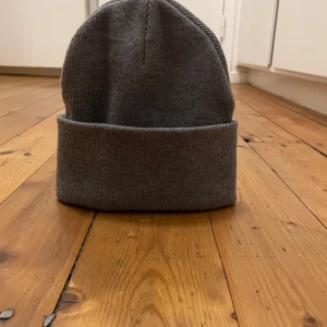Grå mössa - Snygg och enkel grå ribbad mössa från Åhlens Accessories. Perfekt för kyliga dagar med sin stilrena design och bekväma passform.