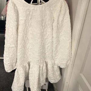 Vit klänning med öppen rygg och knyt - Superfin klänning köpt från Nelly. Klänningen är aldrig använd och med lappen kvar! Klänningen har en fin struktur och är lite utsvängd längst ner, perfekt att ha som studentklänning🥰