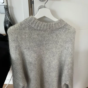Grå stickad tröja från COS - Säljer en stilren grå stickad tröja från COS. Tröjan har en klassisk design med rund hals och långa ärmar, perfekt för kyligare dagar. Den mjuka ullblandningen ger en skön och varm känsla. Passar utmärkt till både jeans och kjol. Knappt använd, och i väldigt bra skick !! ❤️
