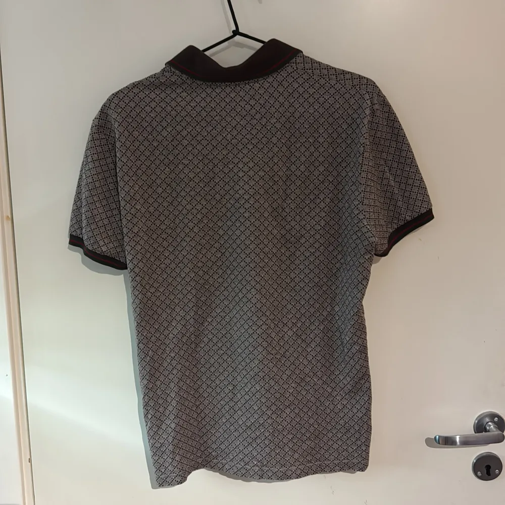 Säljer en stilren pikétröja från Gucci med ett diskret mönster i beige och brunt. Tröjan har korta ärmar och en klassisk krage med knappar framtill. Perfekt för en avslappnad men ändå elegant look. (M) sitter som en s för att den är slimfit . Neuletakit & Villapaidat.