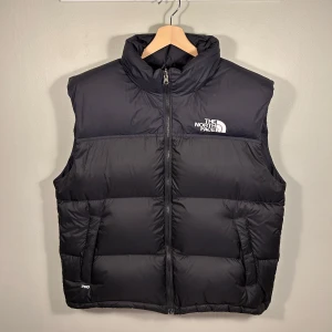 Svart dunväst från The North Face - Säljer en svart dunväst från The North Face med dragkedja och hög krage. Västen säljas pga fel storlek och den är i 8/10 skick. Perfekt för kyliga dagar! Nypris runt 3000kr.